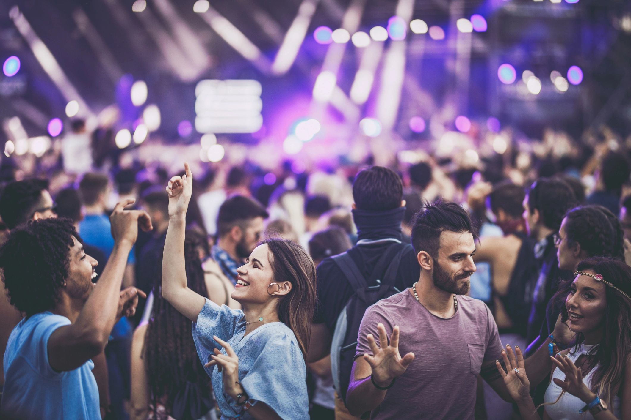 Young carefree couples having fun while dancing on a music concert.